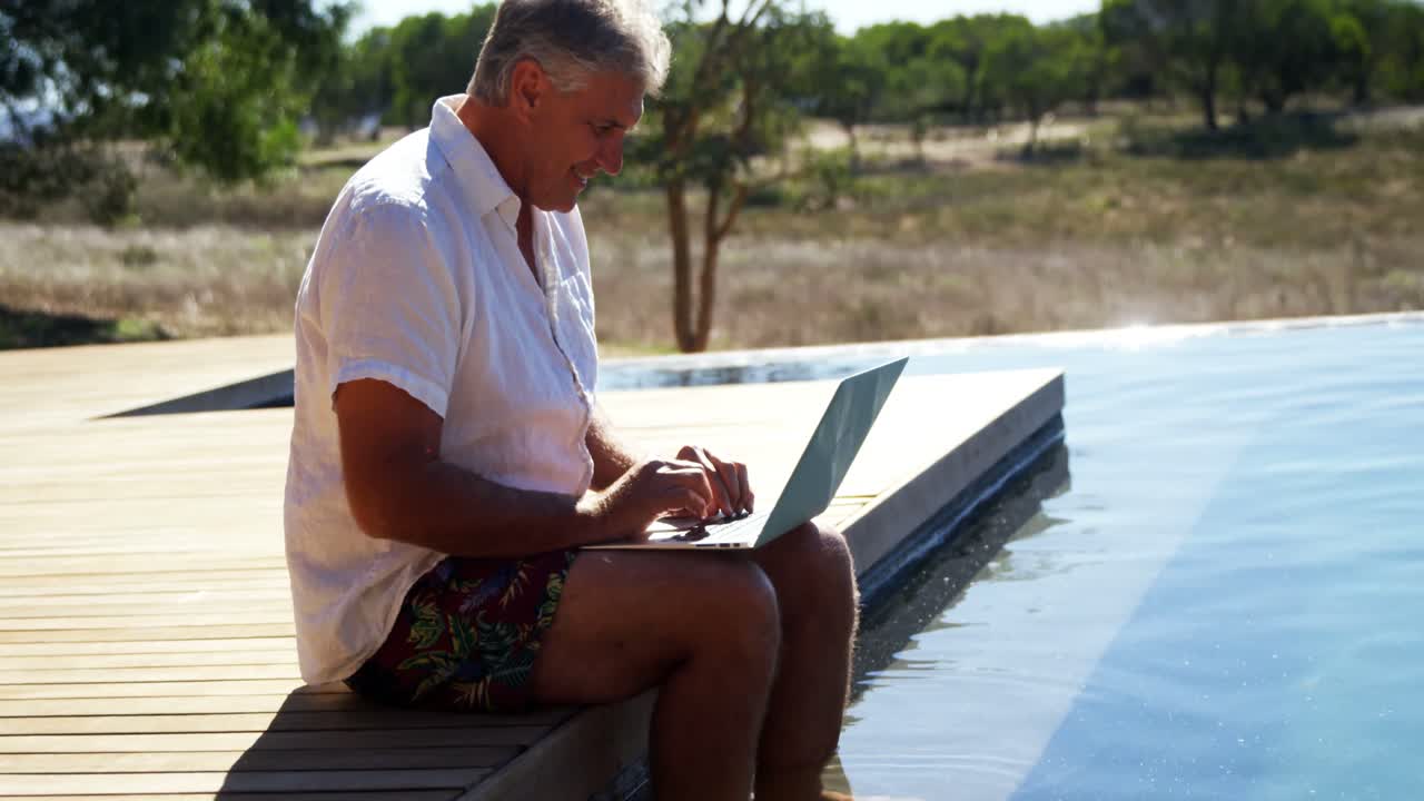 hombre usando computadora portátil cerca de la piscina 4k