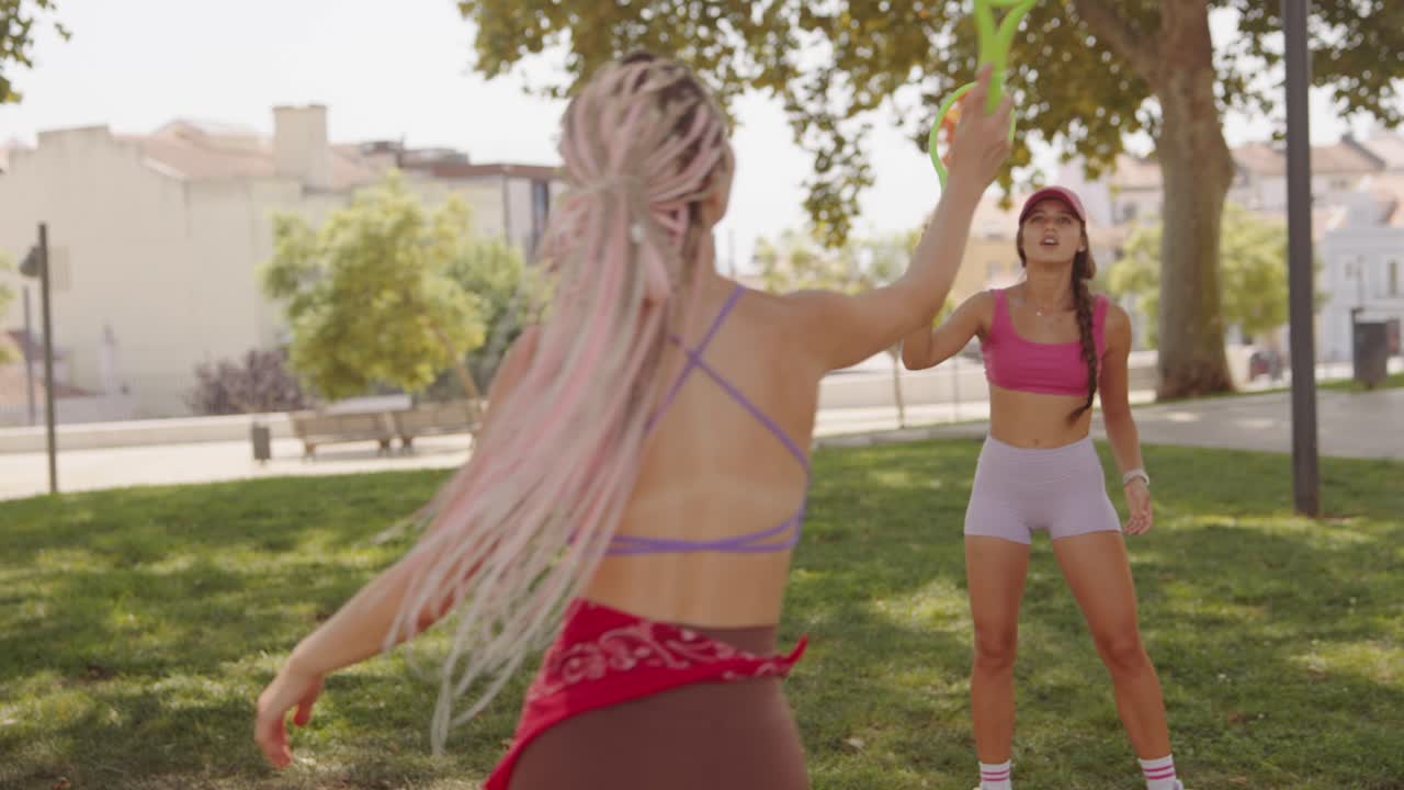 Two women playing tennis in the park