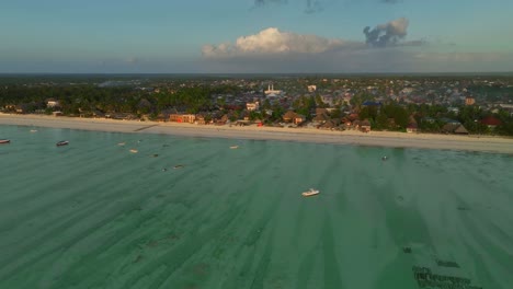 "watch as the drone captures paje, zanzibar at sunset: aerial view of beach, cityscape, and golden hour glow