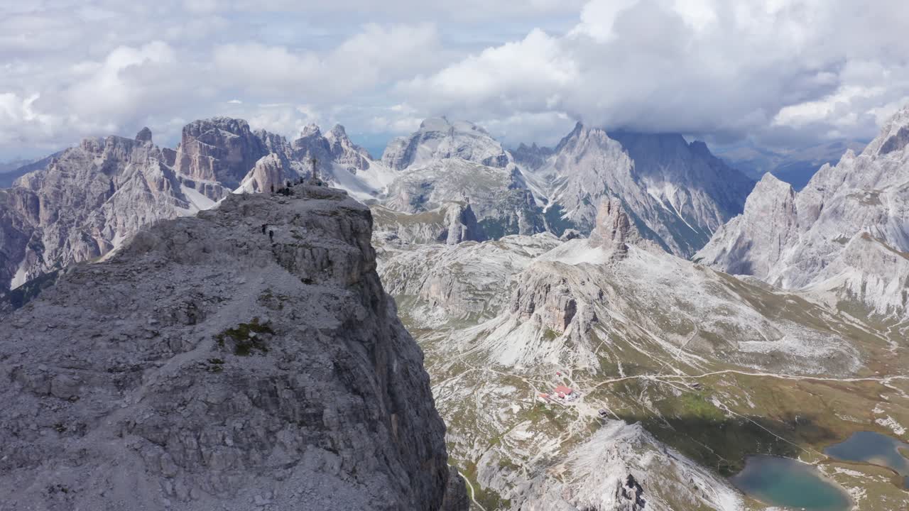 toma de drone del pico de la montaña en tre cime, cruz de la cumbre que revela rifugio localli en el valle de abajo