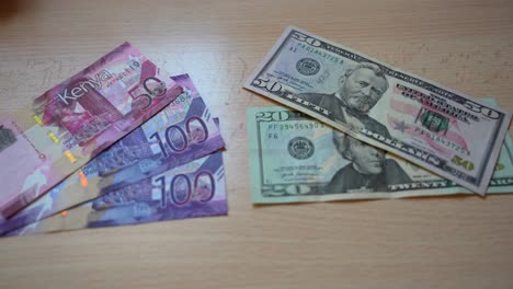 Primer-Plano-De-Los-Billetes-En-Chelines-Kenianos-Junto-A-Los-Billetes-En-Dólares-Estadounidenses,-Cambio-De-Moneda