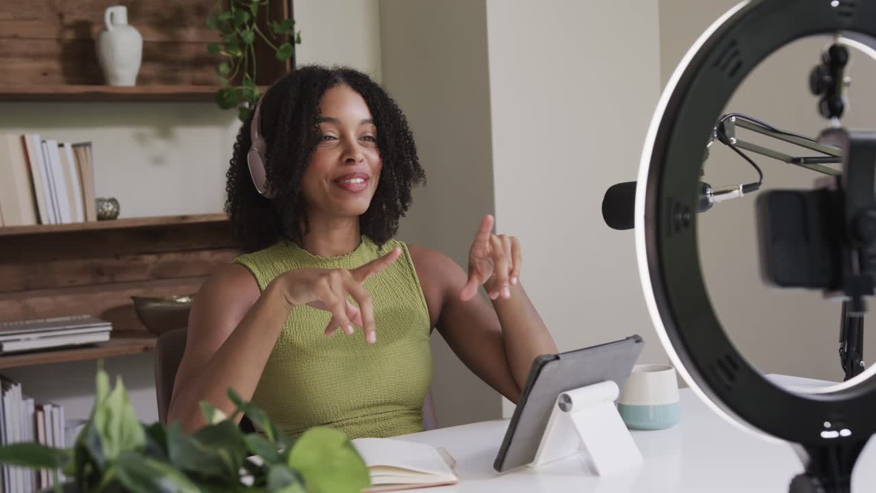 Camera starting, ring light turning on African American woman conducting in office gesturing tablet