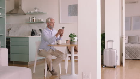 happy old man using smartphone texting browsing online reading social media messages enjoying relaxing retirement lifestyle at home