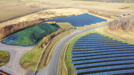 a drone flies over a huge photovoltaic open space installation consisting of many solar panels