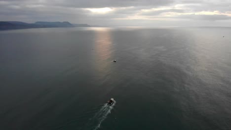 Aerial shot of a Fishing Boat leaving Lyme Regis Dorset on a early morning
