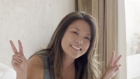 Front-view-of-happy-Japanese-woman-showing-peace-sign-at-camera