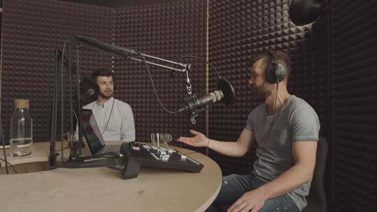Due uomini barbuti hanno una conversazione divertente in uno studio di registrazione radiofonico.