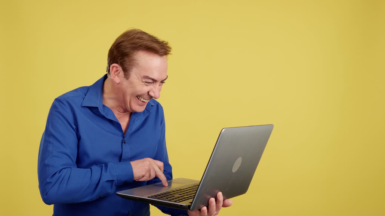Happy Man Using a Laptop on a Yellow Background
