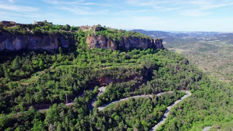 Vista-Aérea-Del-Pueblo-De-Siurana-Y-Una-Carretera-En-Un-Día-Soleado-Con-Nubes-Azules.