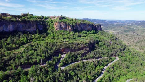 vista aérea de la aldea de siurana y un camino en un día soleado con nubes azules