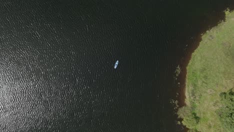 Ascending-Birds-Eye-View-Shot-Of-A-Young-Woman-On-A-Stand-Up-Paddleboard-On-A-Loch