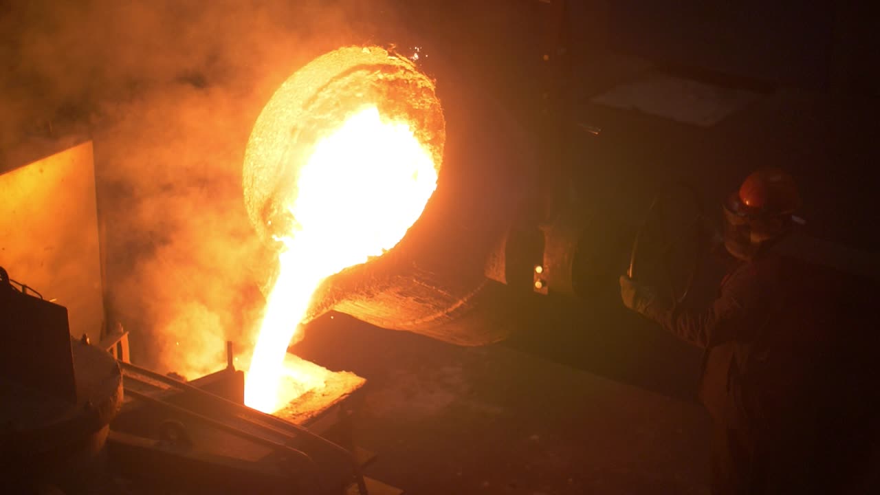 Industrial worker casting metal at metallurgical factory. Molding molten metal