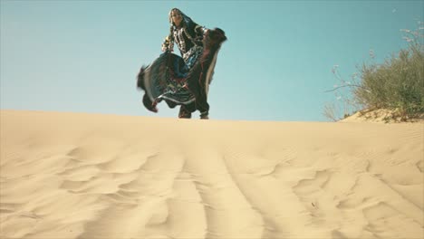 gypsy woman waving her dress on a desert sand dune