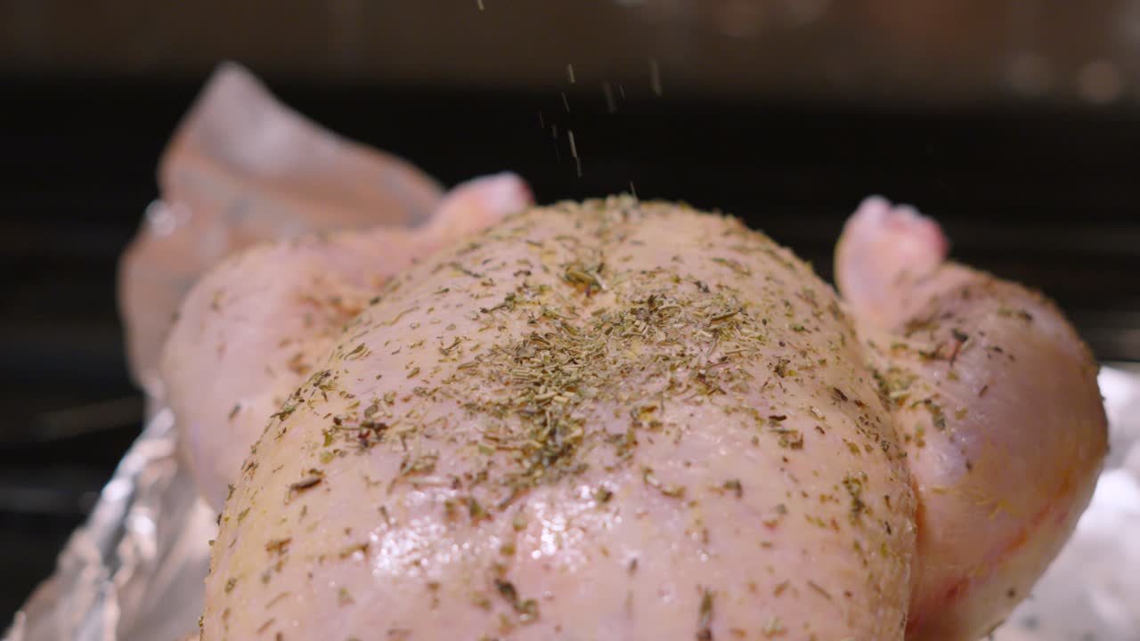 Herby Seasoning Being Drizzled on Raw Whole Free Range Chicken with Ingredients Dropping in Slow Motion Ready for Cooking. Preparing Food Footage 4K.