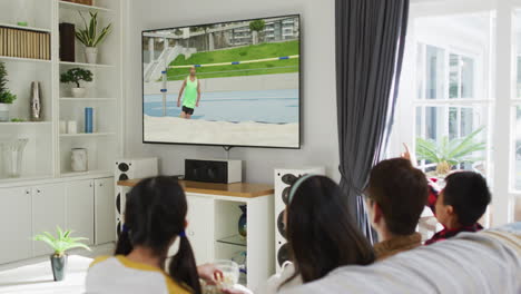 행복 한 가족 이 집 에서 함께 앉아서 tv 에서 육상 하이 점프 대회 를 시청 하고 있다