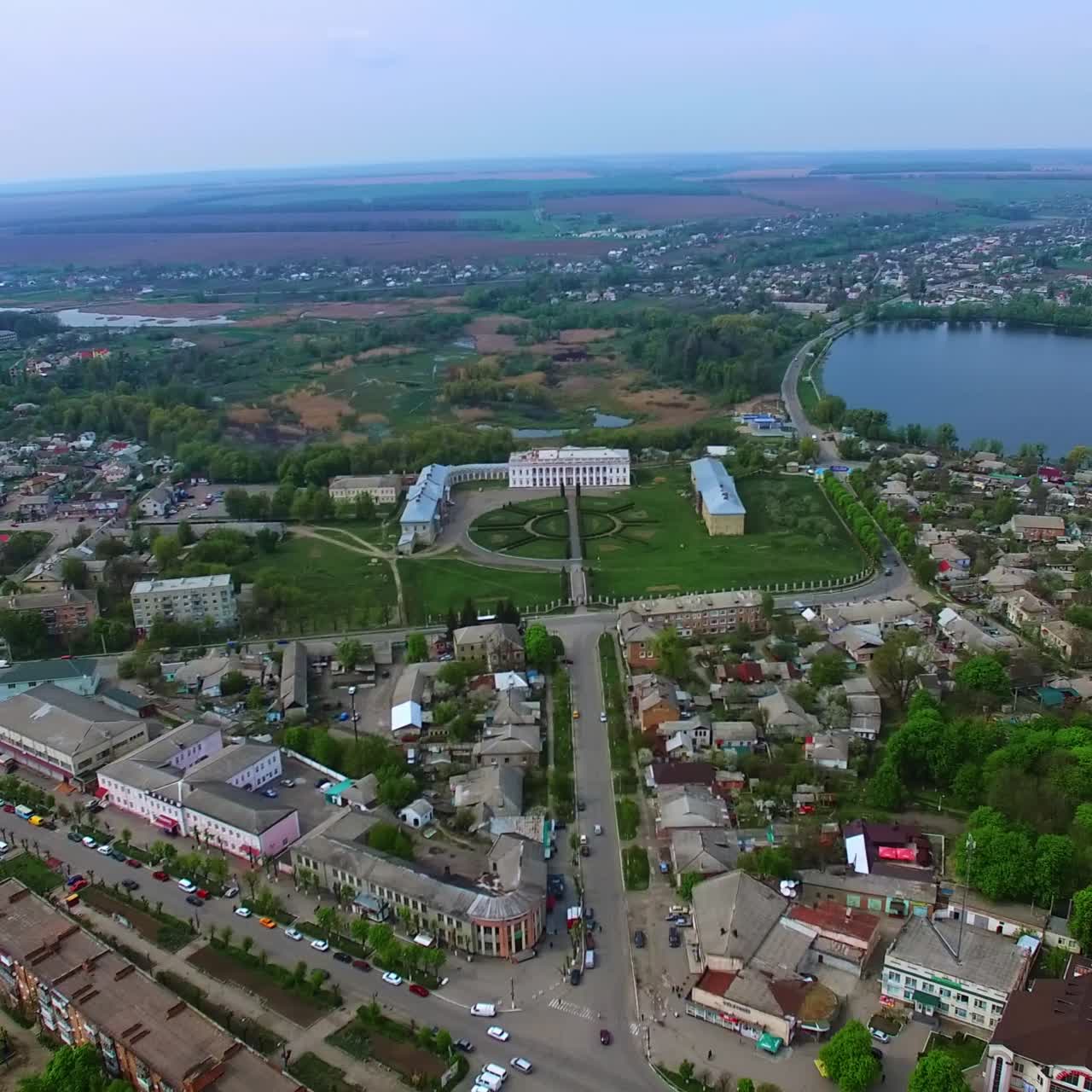Little provincial city of Ukraine. Small pond and historical palaces in the centre. Agricultural fields at backdrop
