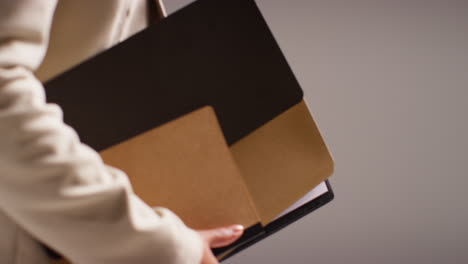 fotografía de estudio de cerca de profesores masculinos y femeninos contra un fondo gris sosteniendo una carpeta bajo el brazo caminando juntos