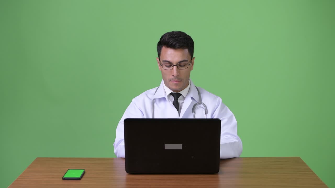 joven hombre hispano guapo médico contra fondo verde