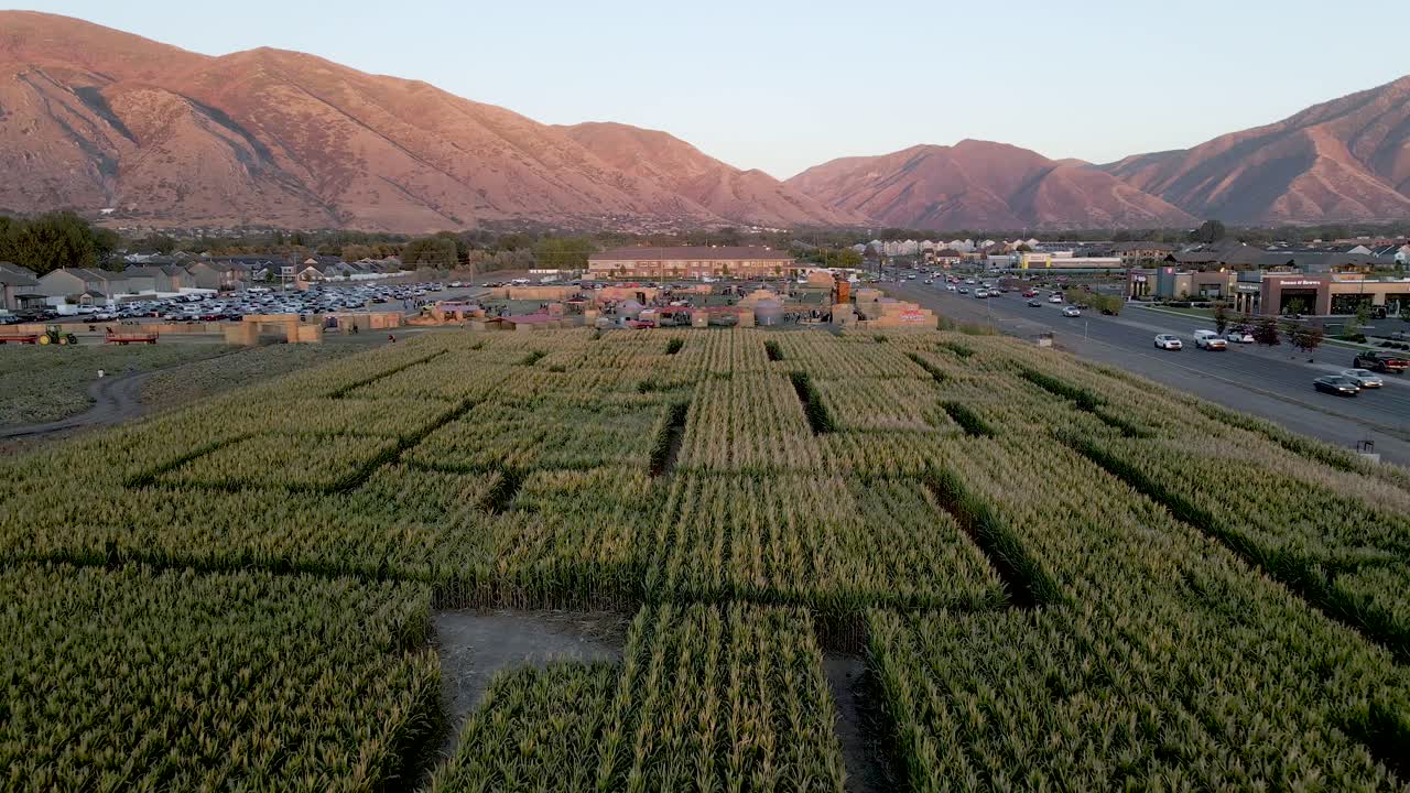 미국 유타에 있는 경치 좋은 산을 배경으로 옥수수 미로 위를 날고 있는 드론