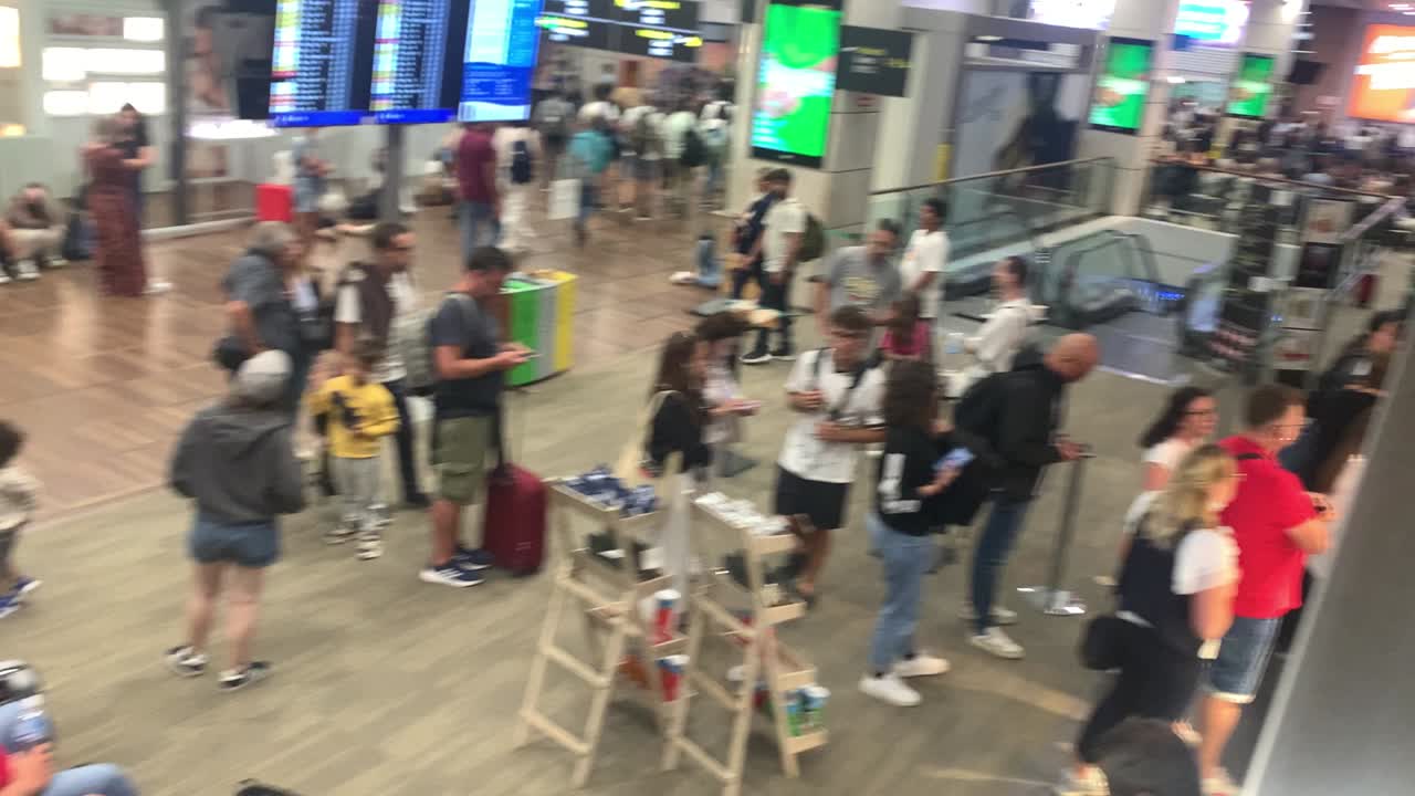People waiting with their luggage in a busy airport terminal
