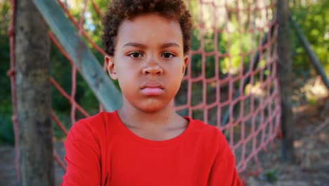 portrait of sad boy standing near net during obstacle course