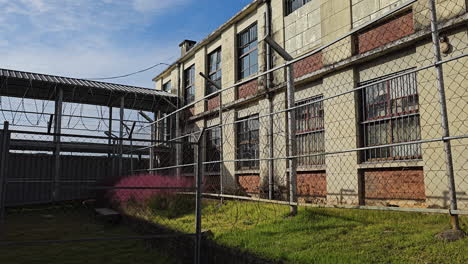 viejo patio de la prisión cerca de alambre de púas y edificio de la cárcel en un día soleado