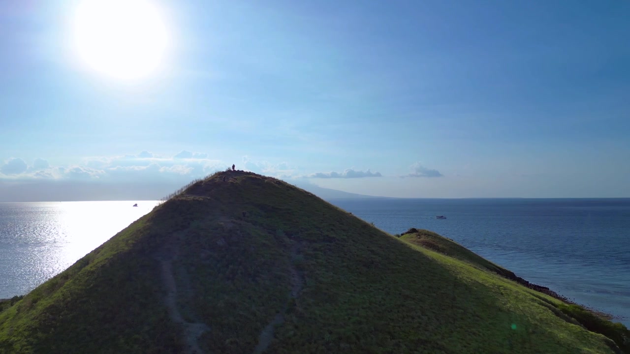 Groene eilandheuvel met uitzicht op de ondiepe blauwe oceaan onder een heldere daghemel. Beste luchtbeeld: panorama met drone, roterend naar rechts