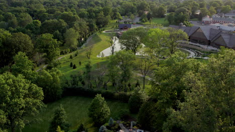 Flyover-pretty-park-and-pond-in-nice-neighborhood-in-summer-at-sunset-in-Town-and-Country-in-St