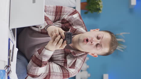 Vertical-video-of-Home-office-worker-man-rejoicing-on-the-phone.