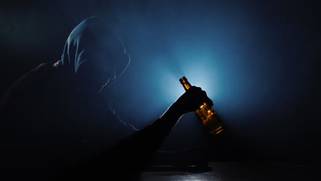 the silhouette of an alcoholic with an empty bottle in his hand