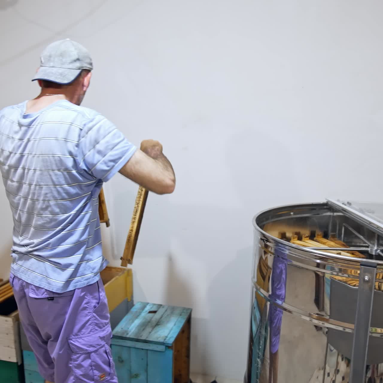 Honey production. Professional apiarist taking out frames from centrifuge machine indoors. Beekeeping process for harvesting natural honey on a farm