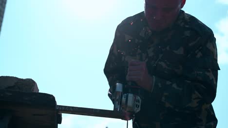 close view handyman cuts metal detail with saw against sky