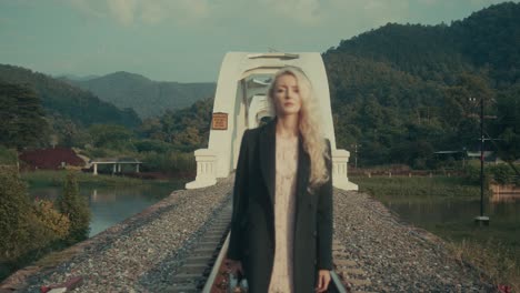 woman walking on train tracks near a bridge