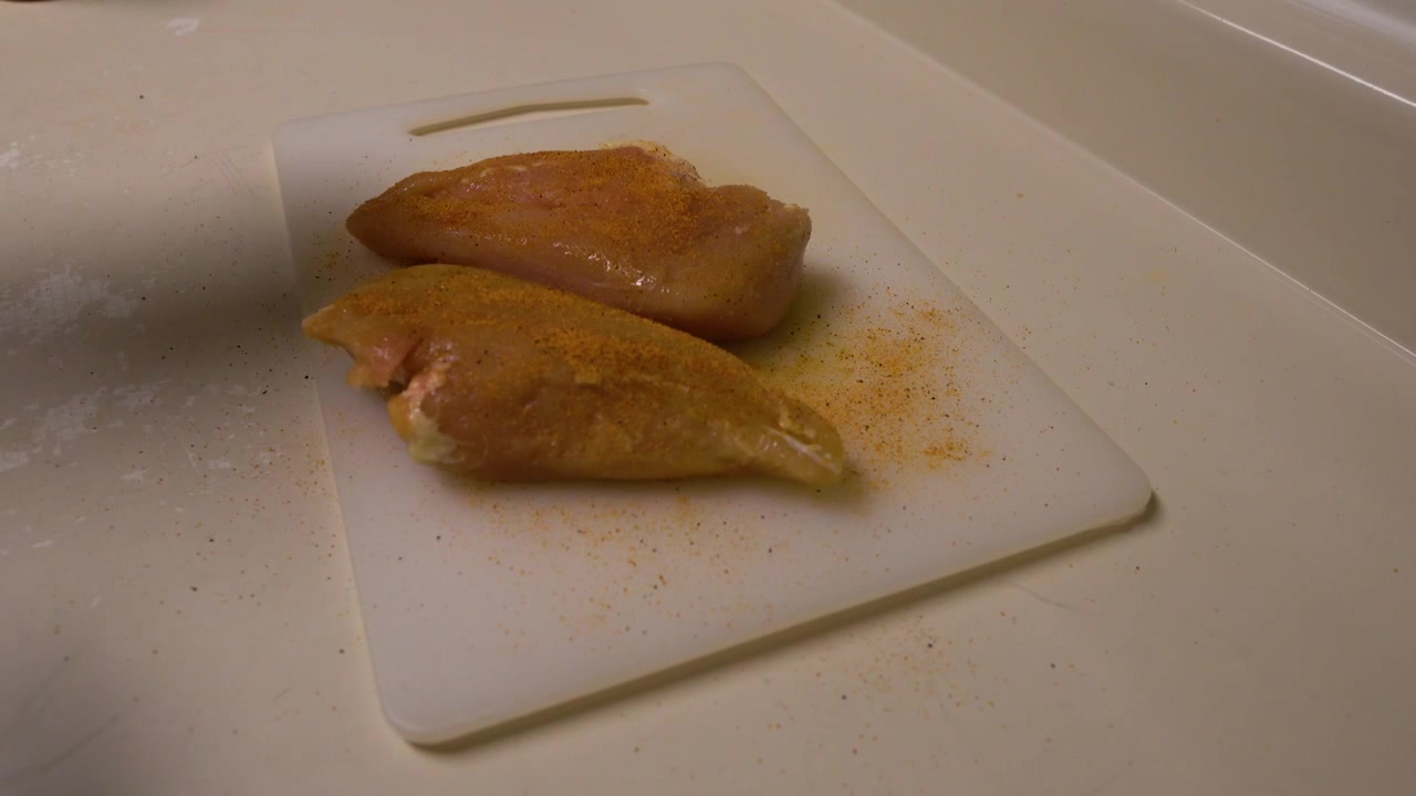 Krydring av rå kylling med et kyllingkrydder før de legges på grillen