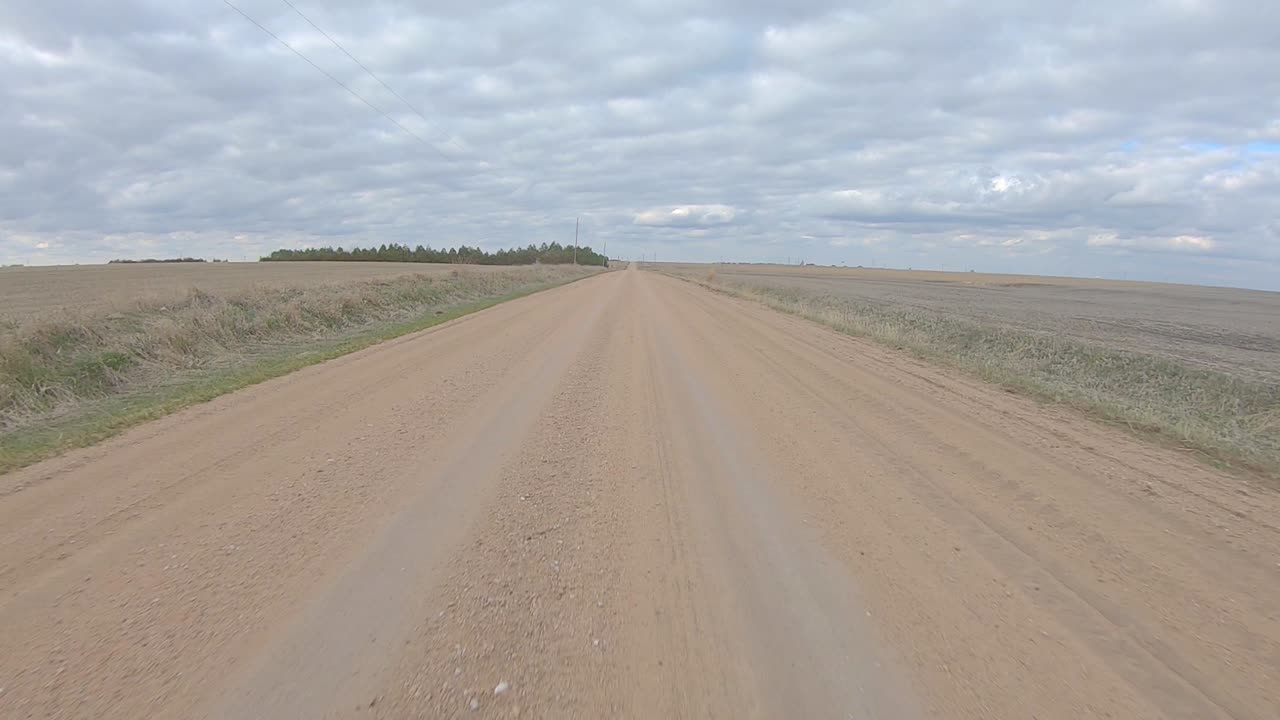 흐린 겨울날 시골 네브래스카를 가로지르는 자갈길의 직선 구간을 운전하는 동안 뒷창 보기