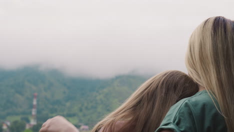 mother strokes little girl hair enjoying misty hills view