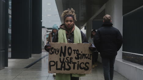 Junger-Amerikanischer-Klimaaktivist-Hält-Ein-Plakat-Und-Protestiert-Gegen-Die-Einwegkunststoffe,-Während-Er-In-Die-Kamera-3-Schaut