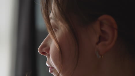 Tranquil-young-woman-looks-into-bright-window-intently