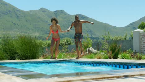 Front-view-of-young-black-couple-jumping-in-the-swimming-pool-4k