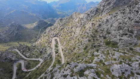 girando revelando tomas de drones de caminos sinuosos subiendo una montaña con numerosas curvas cerradas en un día soleado en sa calobra, mallorca, españa