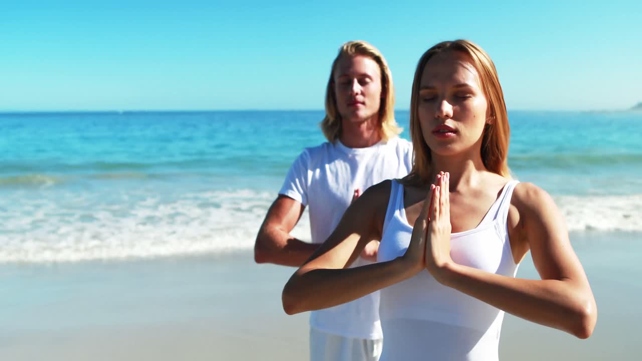 해변 에서 요가 를 하는 부부