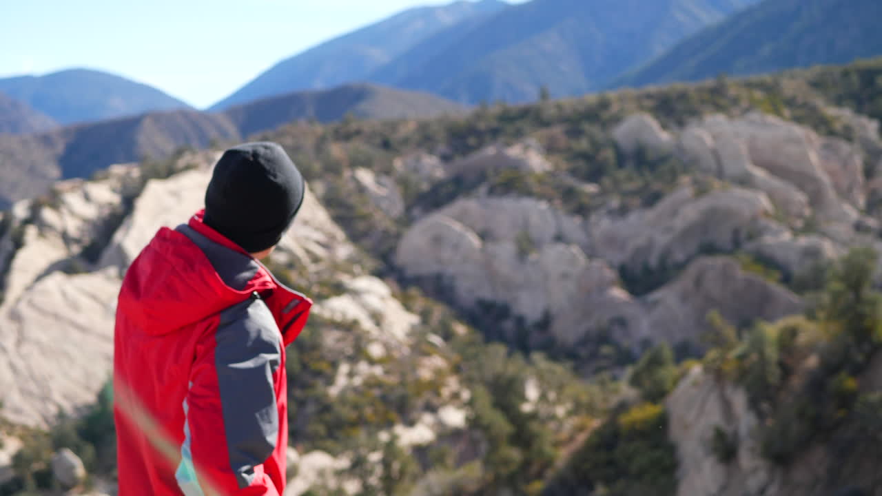 un joven aventurero en una expedición natural planea la próxima etapa de su viaje parado al borde de un acantilado de montaña de california