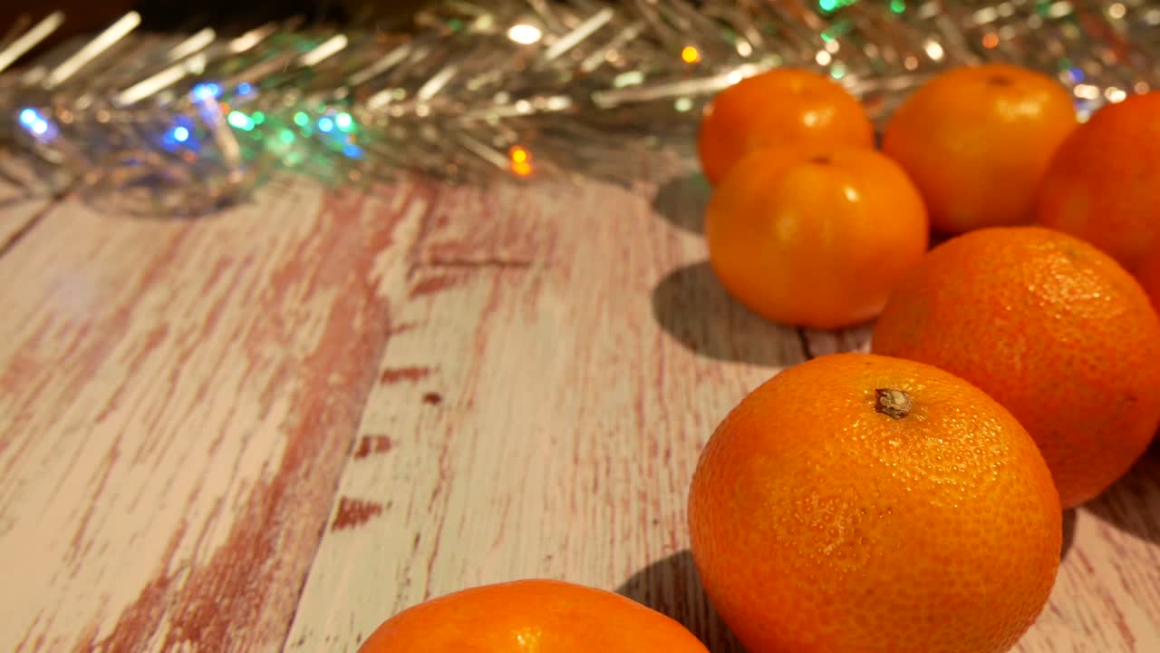 mandarinas en la mesa al lado de las luces de año nuevo y oropel brillante