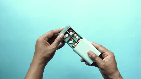 hands holding a pill organizer with various pills inside