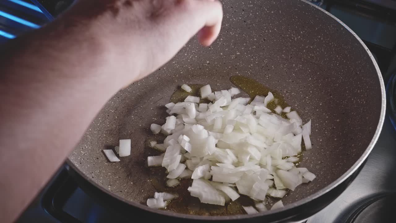 Putting chopped onion on a fryng pan with olive oil
