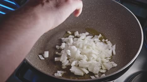 putting chopped onion on a fryng pan with olive oil