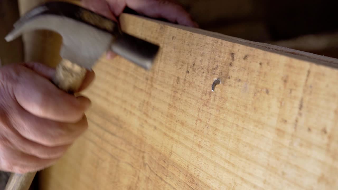 carpintero ajustando un clavo en una tabla de madera