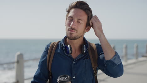 retrato joven atractivo turista bebiendo café relajándose disfrutando de un cálido día de verano en la orilla del mar hombre caucásico guapo disfruta de ocio viajes estilo de vida cámara lenta