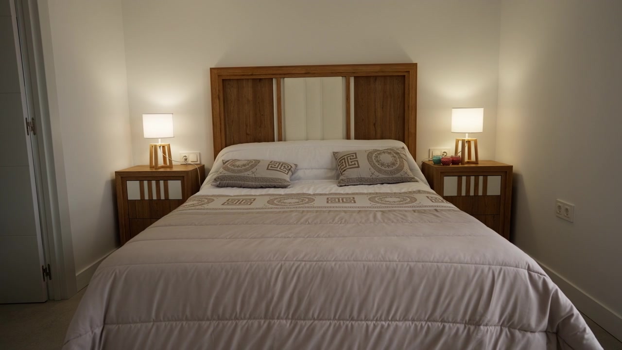 Interno di una camera da letto moderna ed elegante con mobili in legno, illuminazione accogliente e biancheria da letto ben sistemata, che mostra un design domestico contemporaneo e un alloggio confortevole.