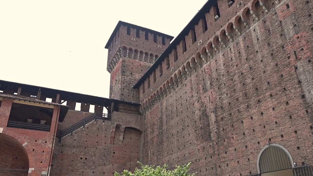 Vista dal basso delle mura in mattoni e della torre del Castello Sforzesco a Milano